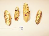 four pieces of gold and red stones on a white surface