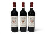 three bottles of red wine sitting next to each other on a white surface