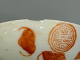 a white bowl with orange designs on it on a table
