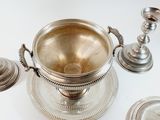 a silver bowl and two silver candles on a white table