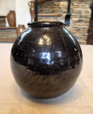 un vase noir posé sur une table devant une cheminée
