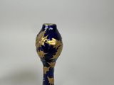 blue and gold vase on a white table with a white background