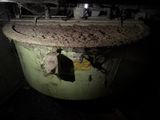 a large green pot with dirt on it in a dark room