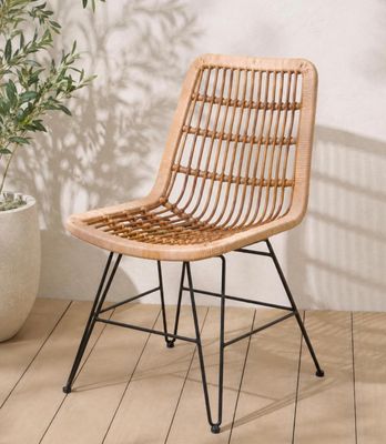 an image of a rattan chair sitting on a wooden floor next to a potted plant