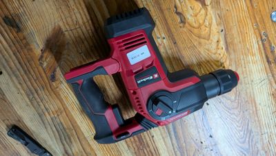 une perceuse filaire et un marteau sur un plancher en bois