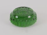 a green glass container with a lid on a white surface