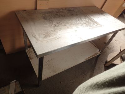 a small table with a metal top in the corner of a room