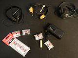 une table noire sur laquelle se trouvent un casque, un chargeur et d'autres appareils électroniques
