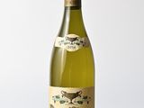 La bouteille de vin blanc est posée sur une table en bois.