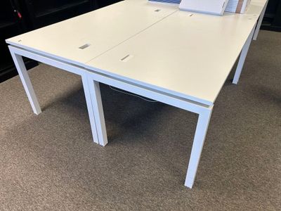 une table blanche sur laquelle est posé un ordinateur portable, au milieu d'une pièce