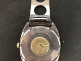 a close up of a watch on a black surface with a metal band