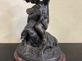statue en bronze représentant un garçon avec un chien, posée sur un socle en marbre