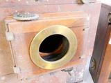 an old camera sitting on the floor next to a wooden cabinet