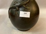 a black vase with a lizard on it on a white surface