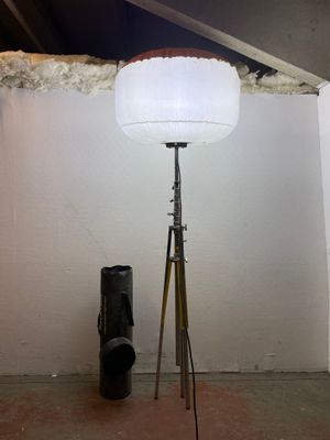 a lamp that is on a tripod next to a bag