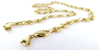 a close up of a gold necklace with a chain on a white surface