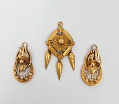 trois bijoux en or sont exposés sur un fond blanc