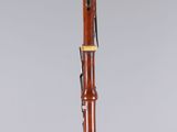 a wooden bassoon on a clear surface with a grey background