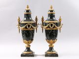 pair of black and gold vases with handles on marble bases