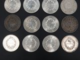 six different types of silver coins on a black surface