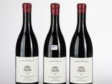 trois bouteilles de vin rouge posées sur une table blanche