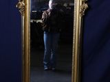 un miroir à cadre doré dans lequel une femme se prend en photo