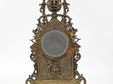 a gold clock with a mirror on top of it
