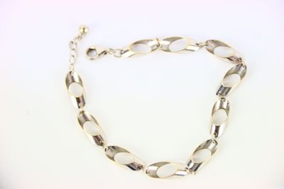 gros plan d'un bracelet en chaîne en argent sur une surface blanche