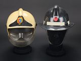 two fire fighters helmets on display on a black surface