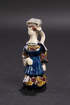 une figurine représentant une femme vêtue d'une robe bleue et d'un chapeau