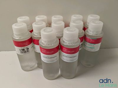 Des flacons de gel hydroalcoolique sont alignés sur une surface blanche