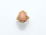 une bague en or ornée d'une pierre de corail ovale au centre