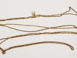 a close up of a gold necklace on a white surface