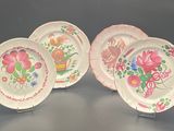 three plates with flowers painted on them sit on a table