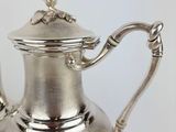 a silver tea pot with a bird on it