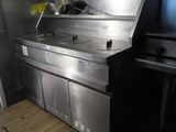 une grande cuisine en inox équipée d'une cuisinière et d'un évier