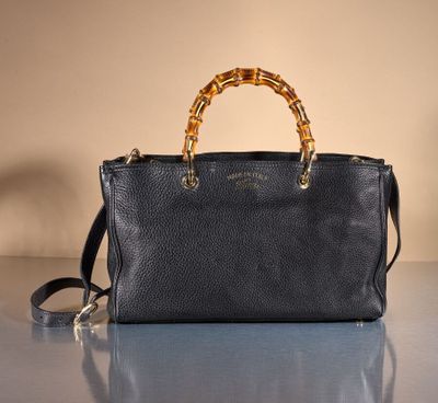 a black purse with bamboo handles sitting on a table