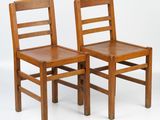 two wooden chairs sitting next to each other on a white surface