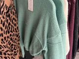 a close up of a rack of sweaters on hangers in a clothing store