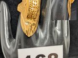 une bague en or ornée d'un poisson, au doigt d'une main