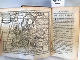 un vieux livre sur lequel figure une carte de l'Europe et une main tenant un bout de papier