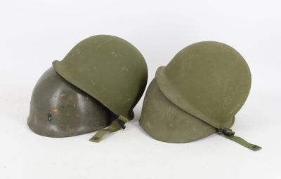 two army green helmets sitting next to each other on a white surface