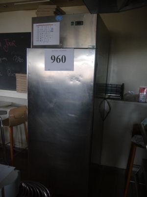 a silver refrigerator in a kitchen with a blackboard on the wall
