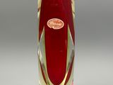 a red vase with a gold rim on a white surface