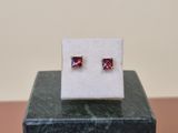 a pair of pink sapphire earrings sitting on top of a marble block