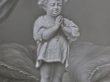 a statue of a child standing on a stool in front of a bed