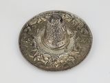 an antique silver plate with a bird on it on a white surface