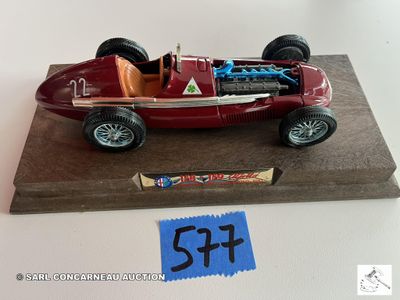 une petite maquette de voiture de course rouge posée sur un socle en bois