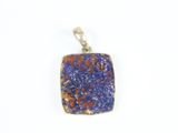 un gros plan d'un pendentif en pierre bleue et orange sur fond blanc