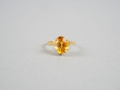 un gros plan d'une bague sertie d'un saphir jaune sur une surface blanche